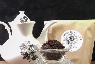 Loose black tea in a cut-glass bowl beside a porcelain teapot.