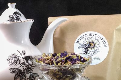 Dried butterfly pea flowers in a cut-glass bowl beside a porcelain teapot.