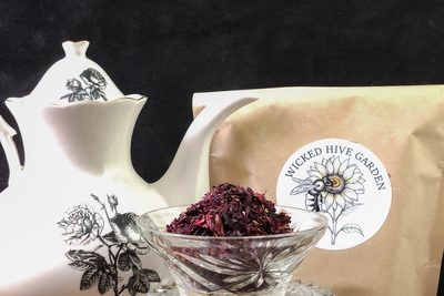 Dried hibiscus petals in a cut-glass bowl beside a porcelain teapot.